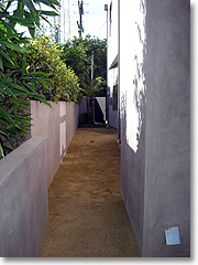 Decomposed granite path with concrete walls along side of house